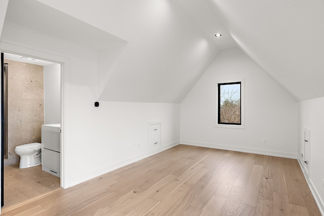 additional living space featuring vaulted ceiling and light hardwood / wood-style flooring