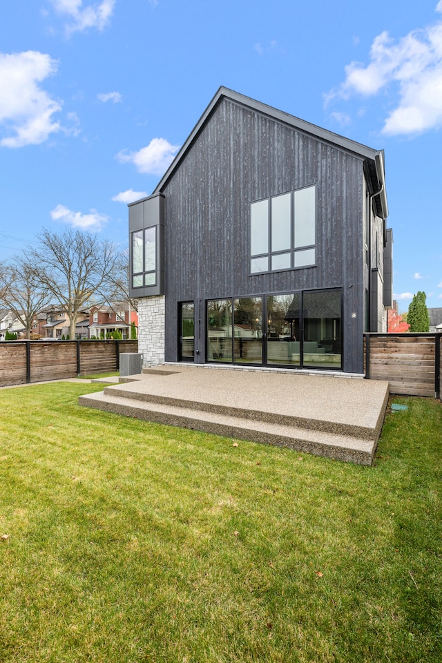 back of property with central AC unit, a patio area, and a lawn