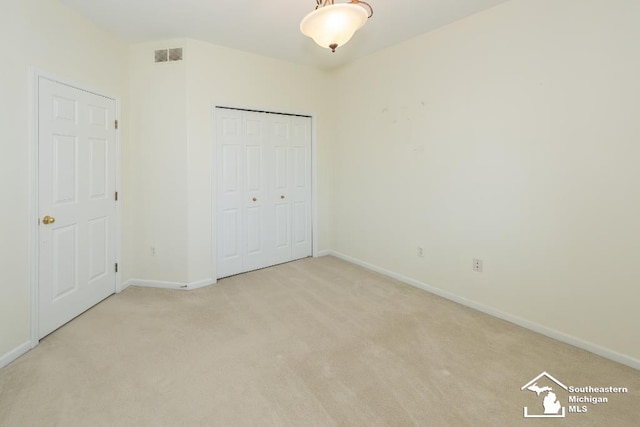 unfurnished bedroom featuring a closet and light carpet