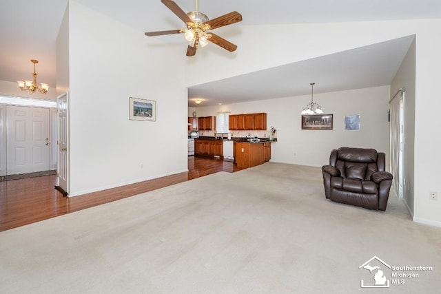 living room featuring ceiling fan with notable chandelier, vaulted ceiling, and carpet