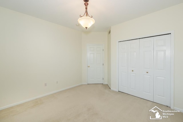 unfurnished bedroom featuring a closet and light colored carpet