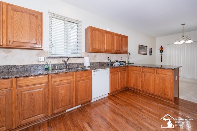 kitchen with kitchen peninsula, decorative light fixtures, an inviting chandelier, white dishwasher, and sink