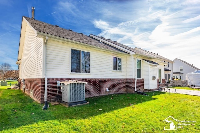 back of property with central AC, a yard, and a patio area