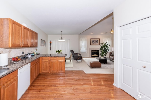 kitchen featuring kitchen peninsula, dishwasher, hanging light fixtures, backsplash, and ceiling fan with notable chandelier