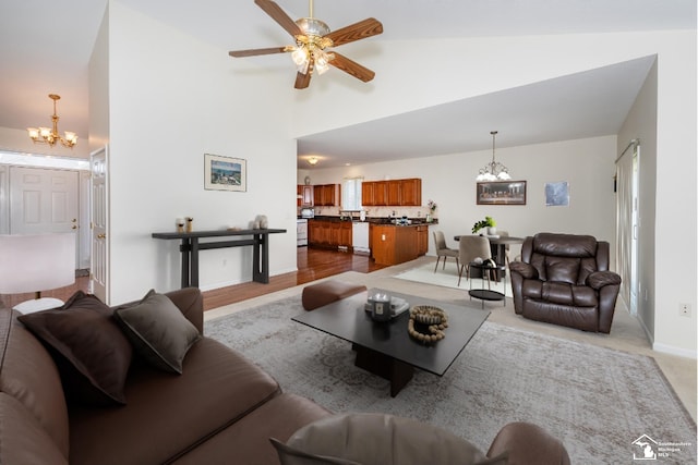 living room with ceiling fan with notable chandelier and vaulted ceiling