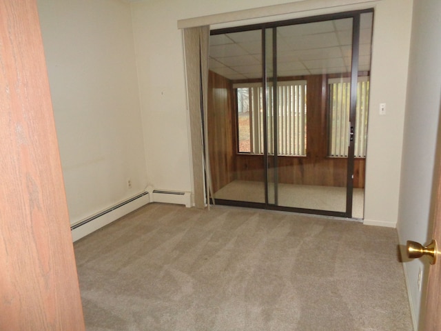 unfurnished room with carpet and a baseboard heating unit