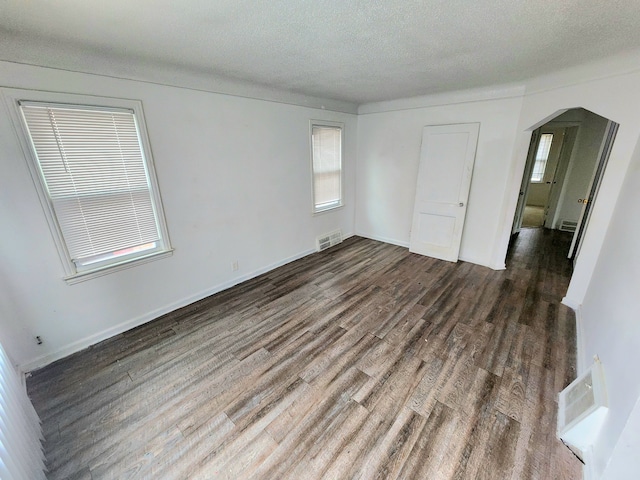 empty room featuring a textured ceiling and dark hardwood / wood-style flooring