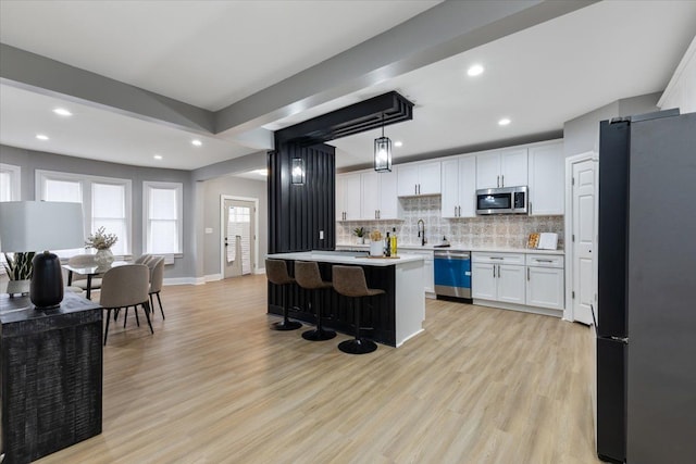 kitchen with white cabinets, pendant lighting, a center island, and stainless steel appliances