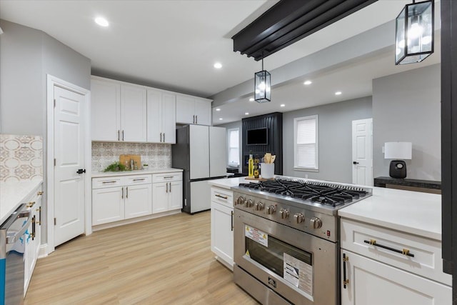 kitchen with white cabinets, pendant lighting, light wood-type flooring, and appliances with stainless steel finishes