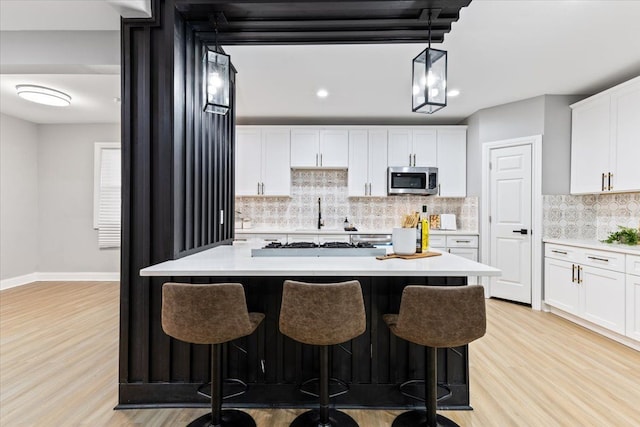 kitchen with decorative light fixtures, white cabinetry, and a kitchen island