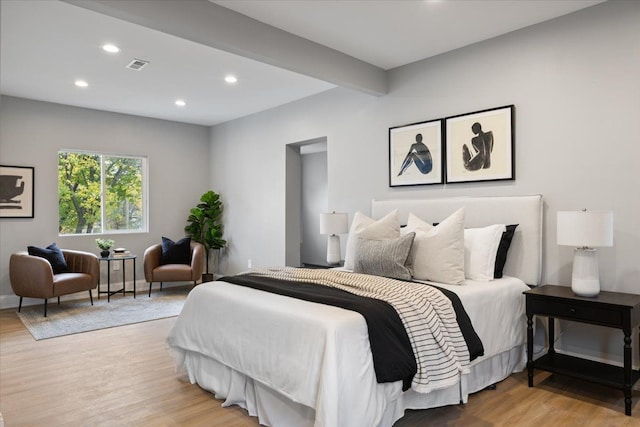 bedroom with beam ceiling and light wood-type flooring