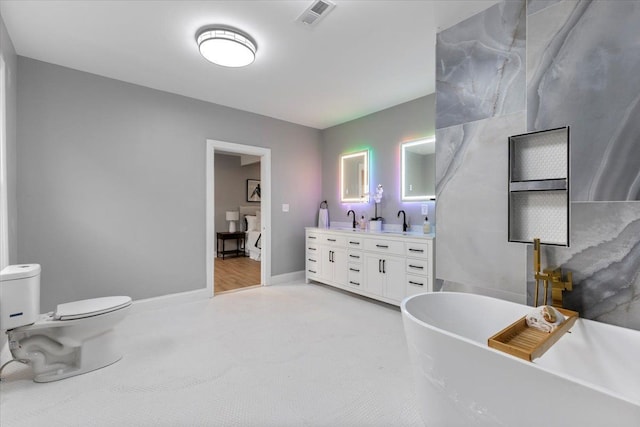 bathroom with a tub, vanity, and toilet