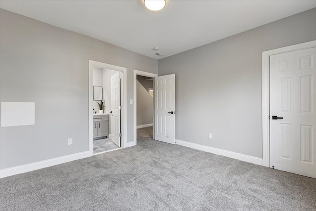 unfurnished bedroom with light carpet and connected bathroom