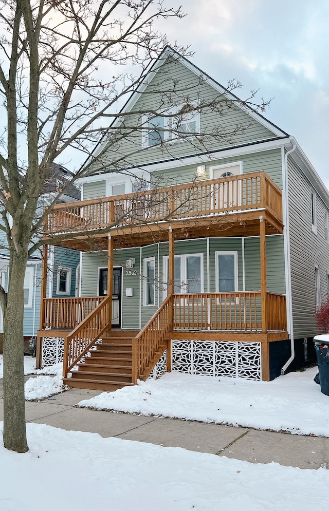 snow covered rear of property with a deck