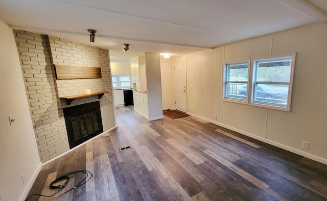 unfurnished living room with hardwood / wood-style flooring, a wealth of natural light, and a brick fireplace