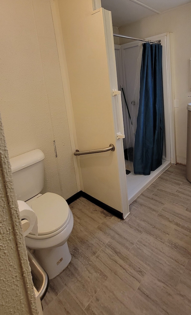 bathroom with a shower with shower curtain, wood-type flooring, and toilet