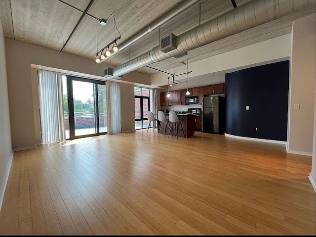 unfurnished living room with light wood-type flooring and rail lighting