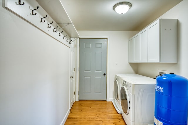 clothes washing area featuring cabinets, washing machine and dryer, and light hardwood / wood-style flooring