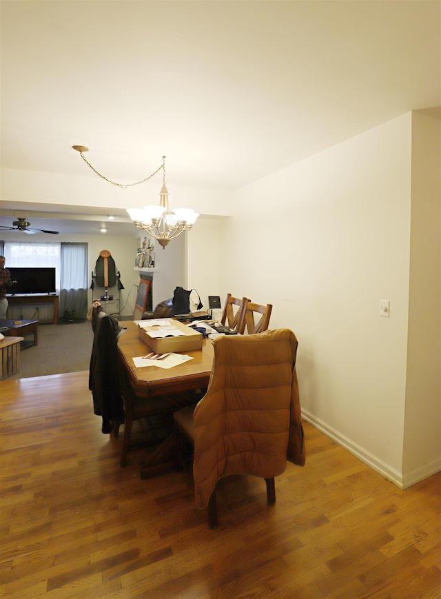 dining area with hardwood / wood-style floors and ceiling fan with notable chandelier