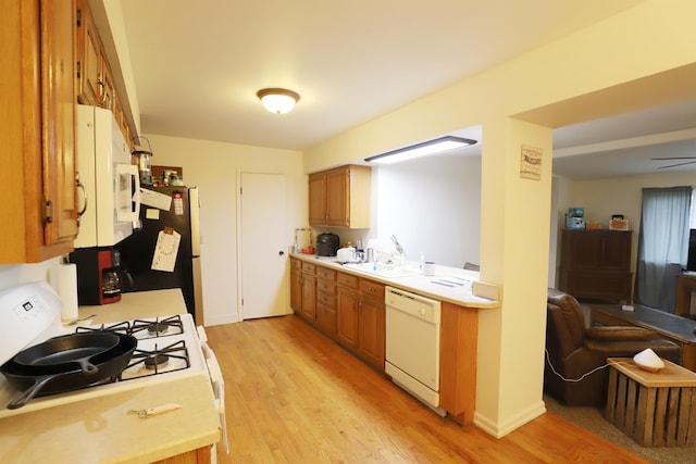 kitchen with ceiling fan, white appliances, sink, and light hardwood / wood-style flooring