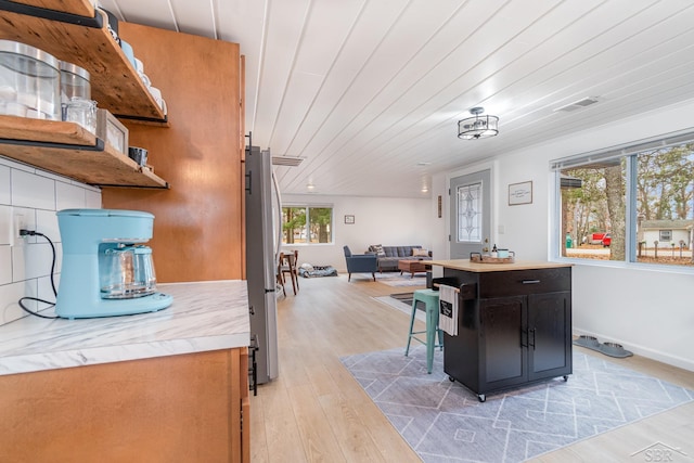 kitchen with plenty of natural light, stainless steel fridge, light wood-type flooring, and wooden ceiling