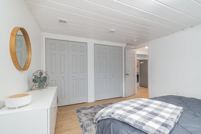 bedroom with light hardwood / wood-style floors and multiple closets