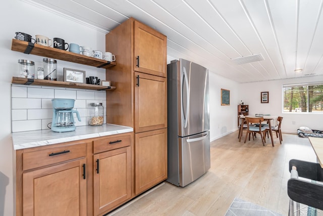 kitchen featuring tasteful backsplash, stainless steel fridge, light hardwood / wood-style floors, and ornamental molding