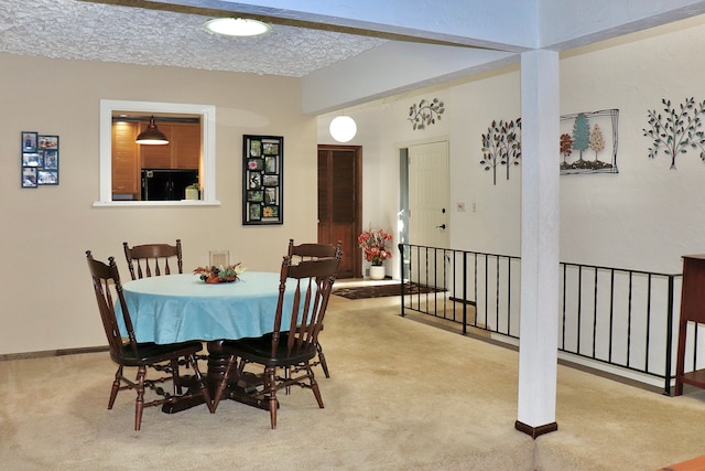 carpeted dining area with a textured ceiling