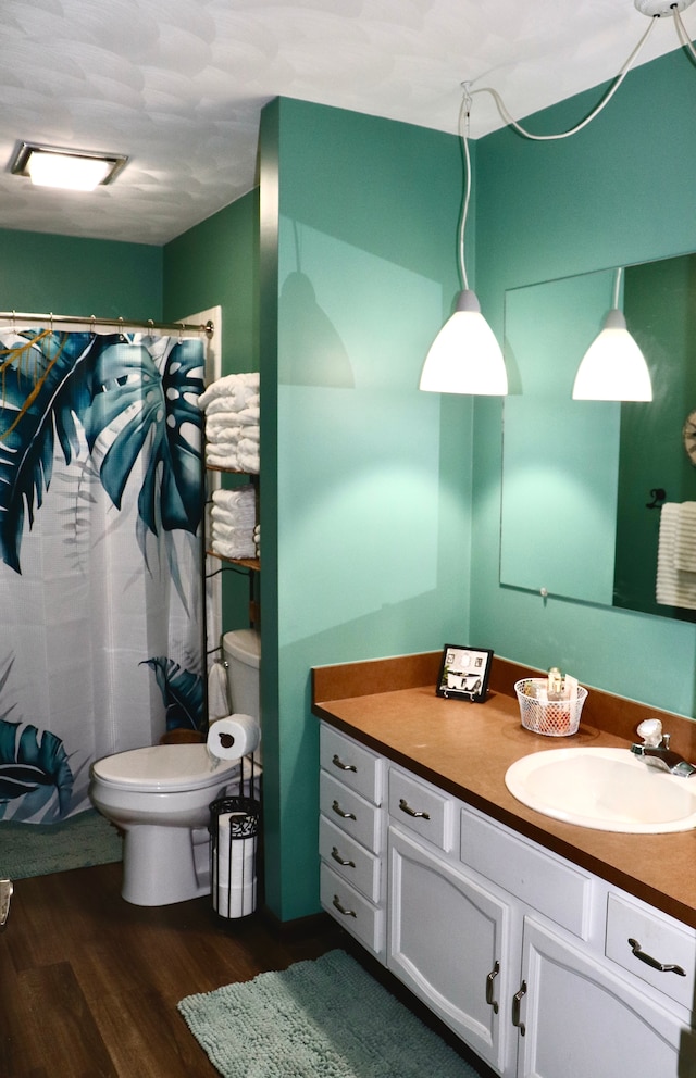 bathroom featuring hardwood / wood-style floors, vanity, toilet, and walk in shower