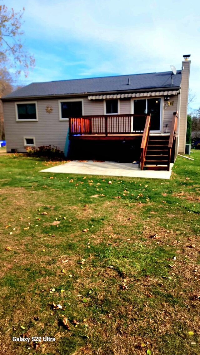 back of property featuring a wooden deck, a yard, and a patio