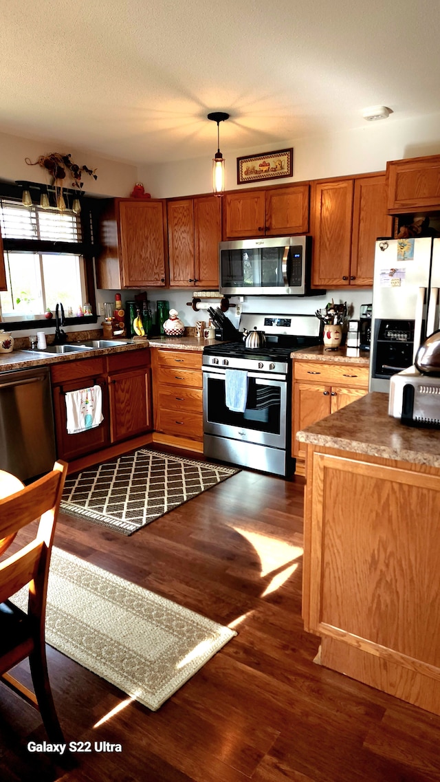 kitchen featuring pendant lighting, dark hardwood / wood-style floors, stainless steel appliances, and a textured ceiling