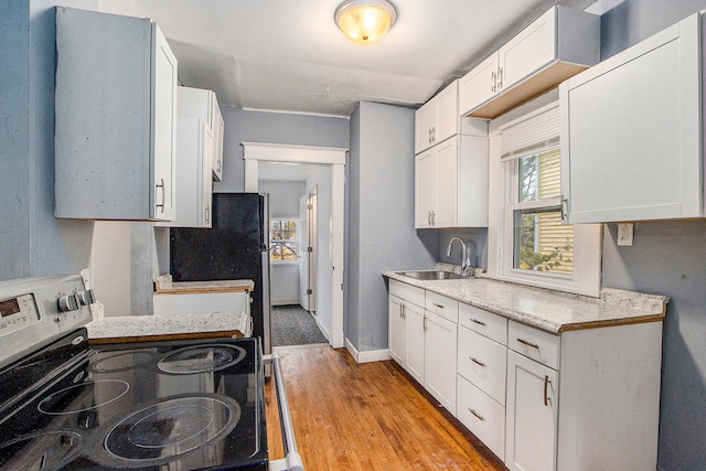 kitchen with range with electric stovetop, sink, white cabinets, and light wood-type flooring