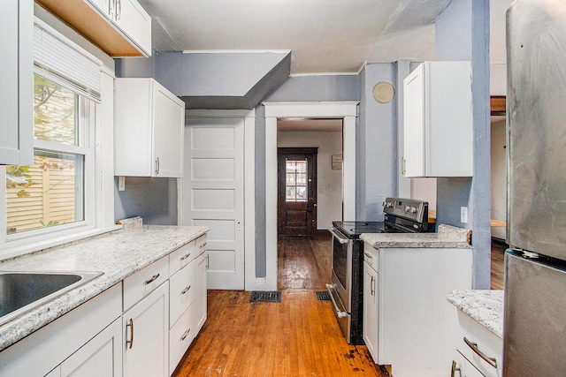 kitchen featuring white cabinetry, light hardwood / wood-style floors, light stone counters, and appliances with stainless steel finishes