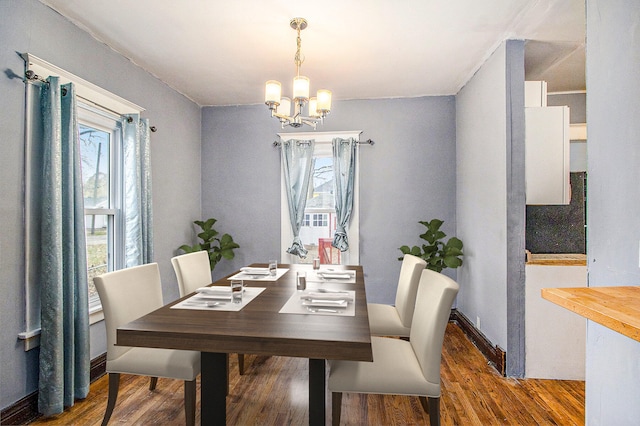 dining area with a notable chandelier and dark hardwood / wood-style flooring