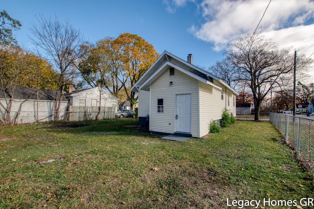 back of house with an outdoor structure and a yard