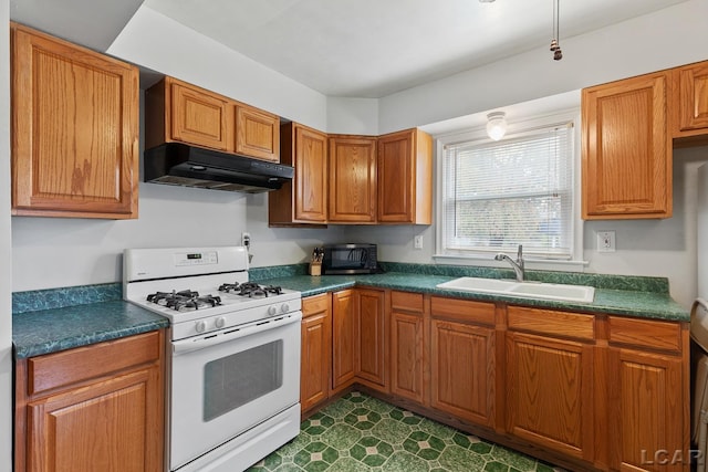 kitchen featuring dark tile patterned flooring, gas range gas stove, and sink