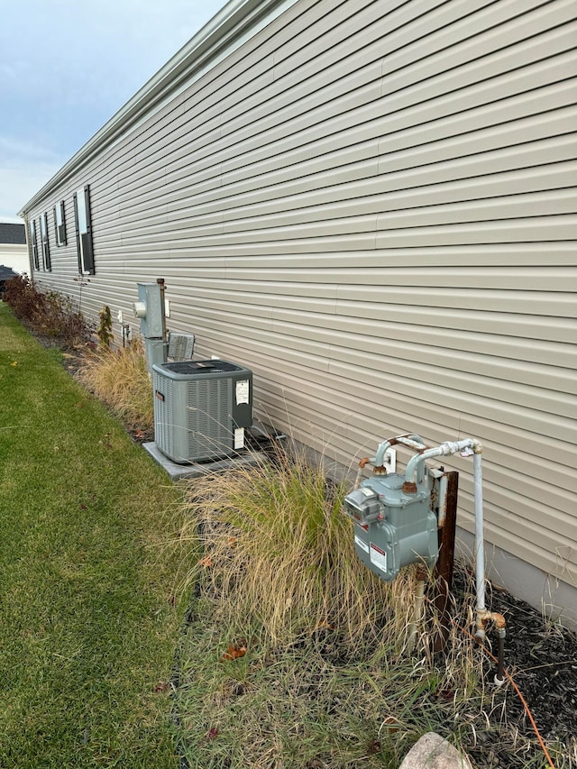 view of side of home featuring a lawn and central air condition unit