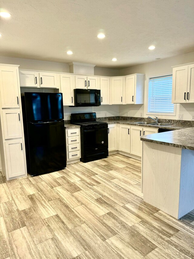 kitchen with sink, white cabinets, black appliances, and light hardwood / wood-style floors