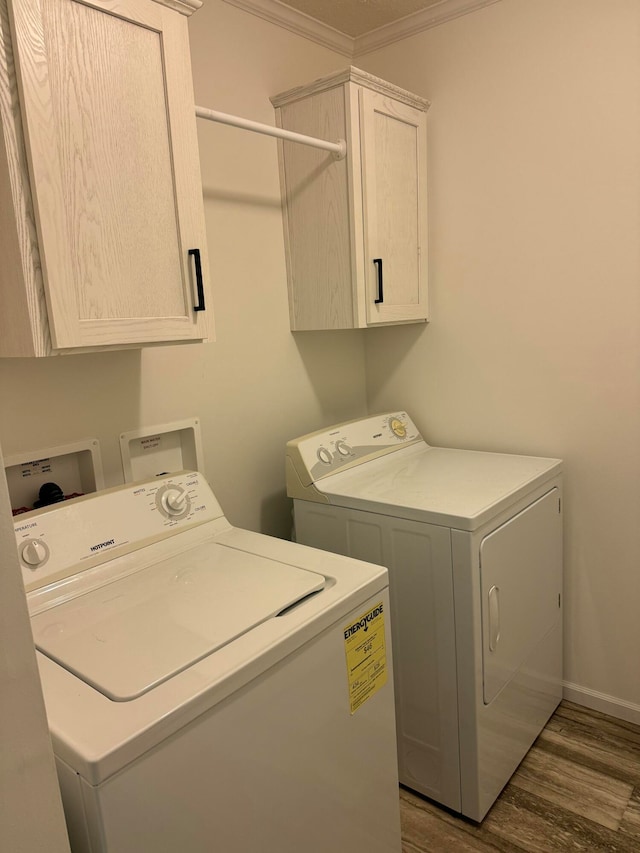 laundry area featuring cabinets, dark wood-type flooring, ornamental molding, and washing machine and clothes dryer