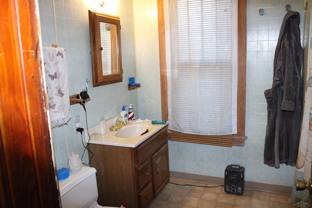 bathroom featuring vanity, tile walls, and toilet