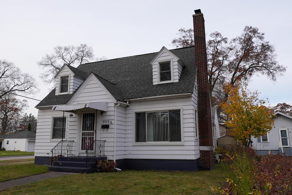 cape cod house featuring a front yard and central AC unit