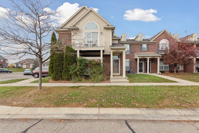 multi unit property with central AC unit, a balcony, and a front yard