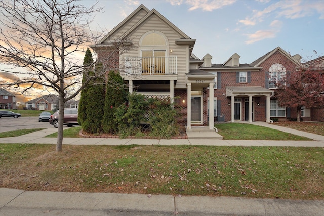 view of front of house with a lawn and a balcony