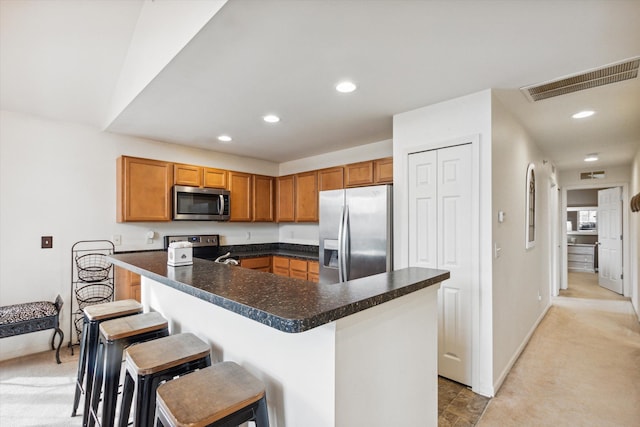 kitchen with a kitchen bar, a center island, light colored carpet, and appliances with stainless steel finishes