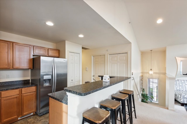 kitchen featuring a center island, lofted ceiling, dark colored carpet, stainless steel refrigerator with ice dispenser, and a breakfast bar area