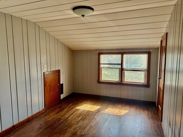 empty room with wooden walls, dark wood-style floors, and baseboards