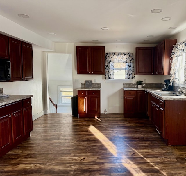 kitchen featuring dark brown cabinets, dark wood-type flooring, black microwave, light countertops, and a sink