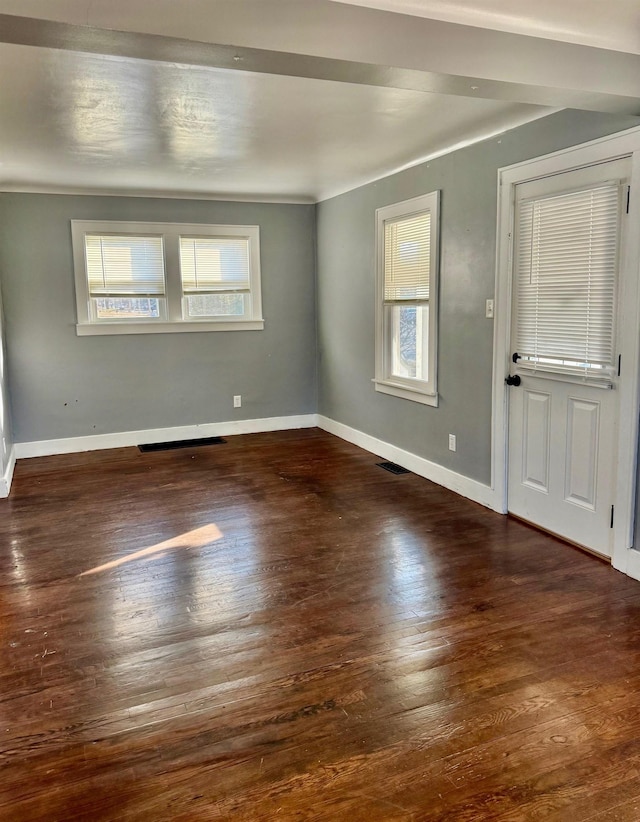 unfurnished room featuring baseboards, a healthy amount of sunlight, and wood finished floors