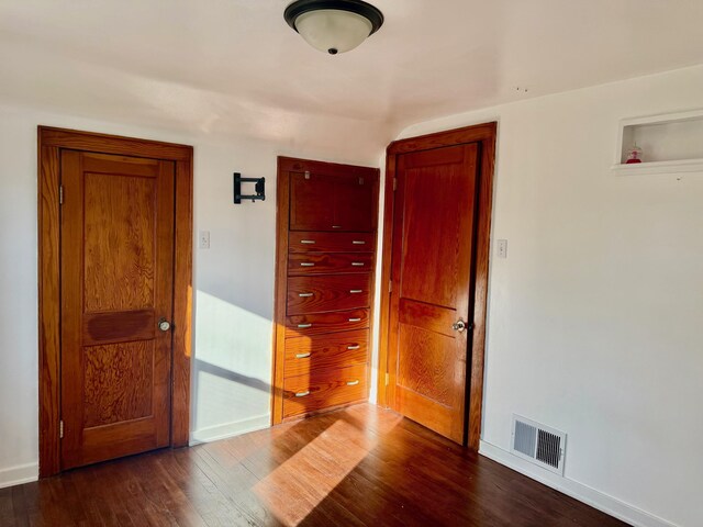 empty room with baseboards, visible vents, and dark wood-style flooring