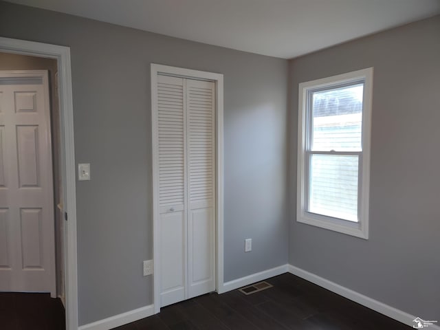 113 Walnut St, Brooklyn, MI 49230 - unfurnished bedroom featuring multiple windows, baseboards, dark wood finished floors, and a closet